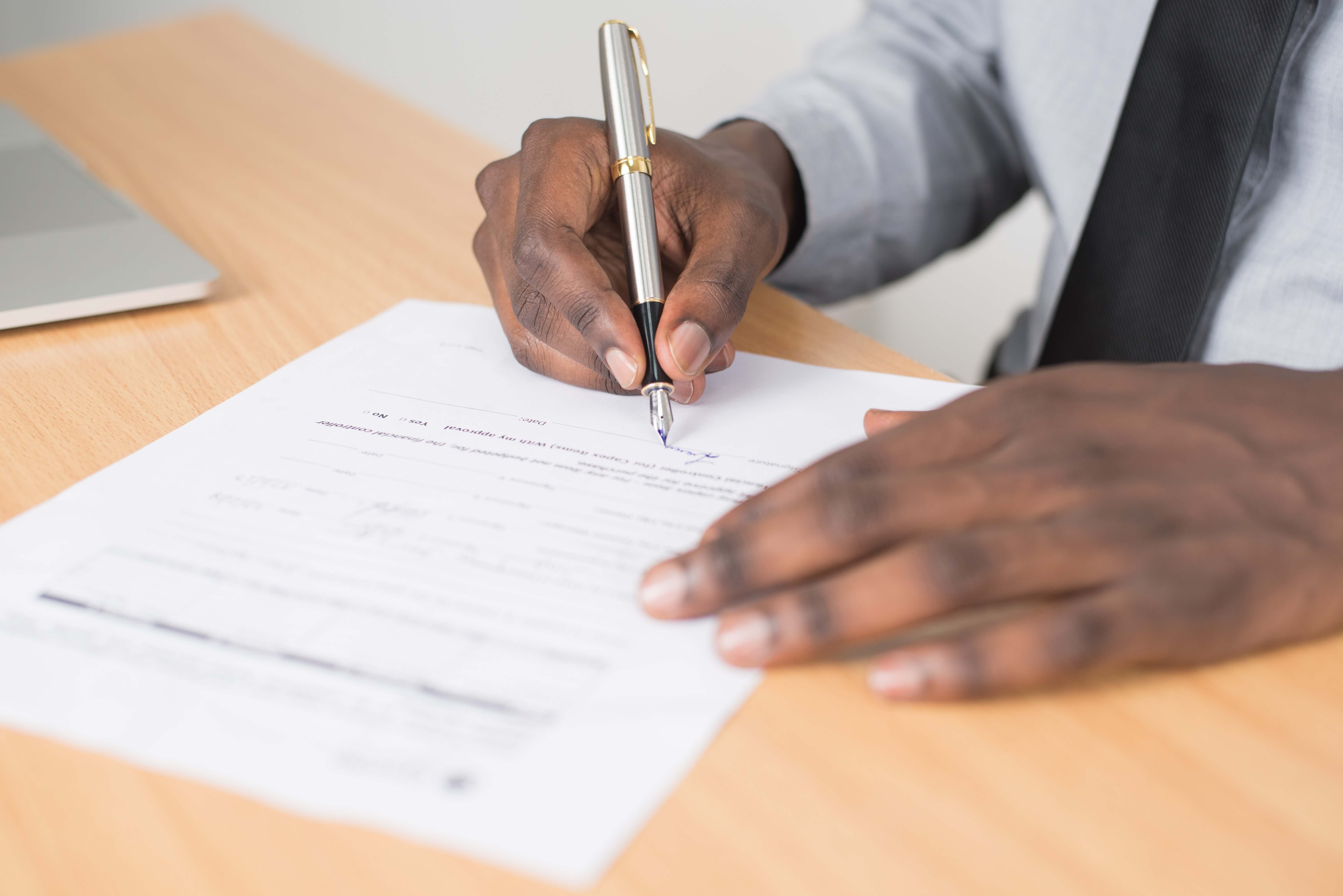 a man signing a document on a desk