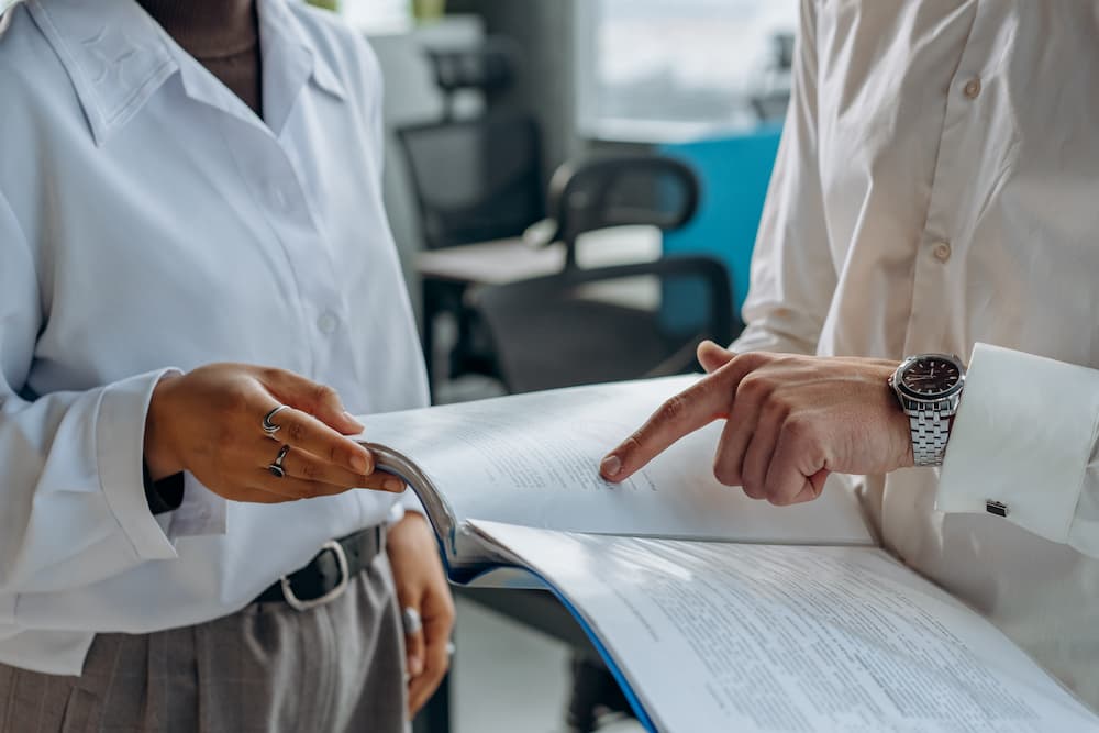 two people in a meeting room, one is holding a piece of paper and the other is holding