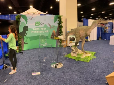 a woman standing next to a dinosaur