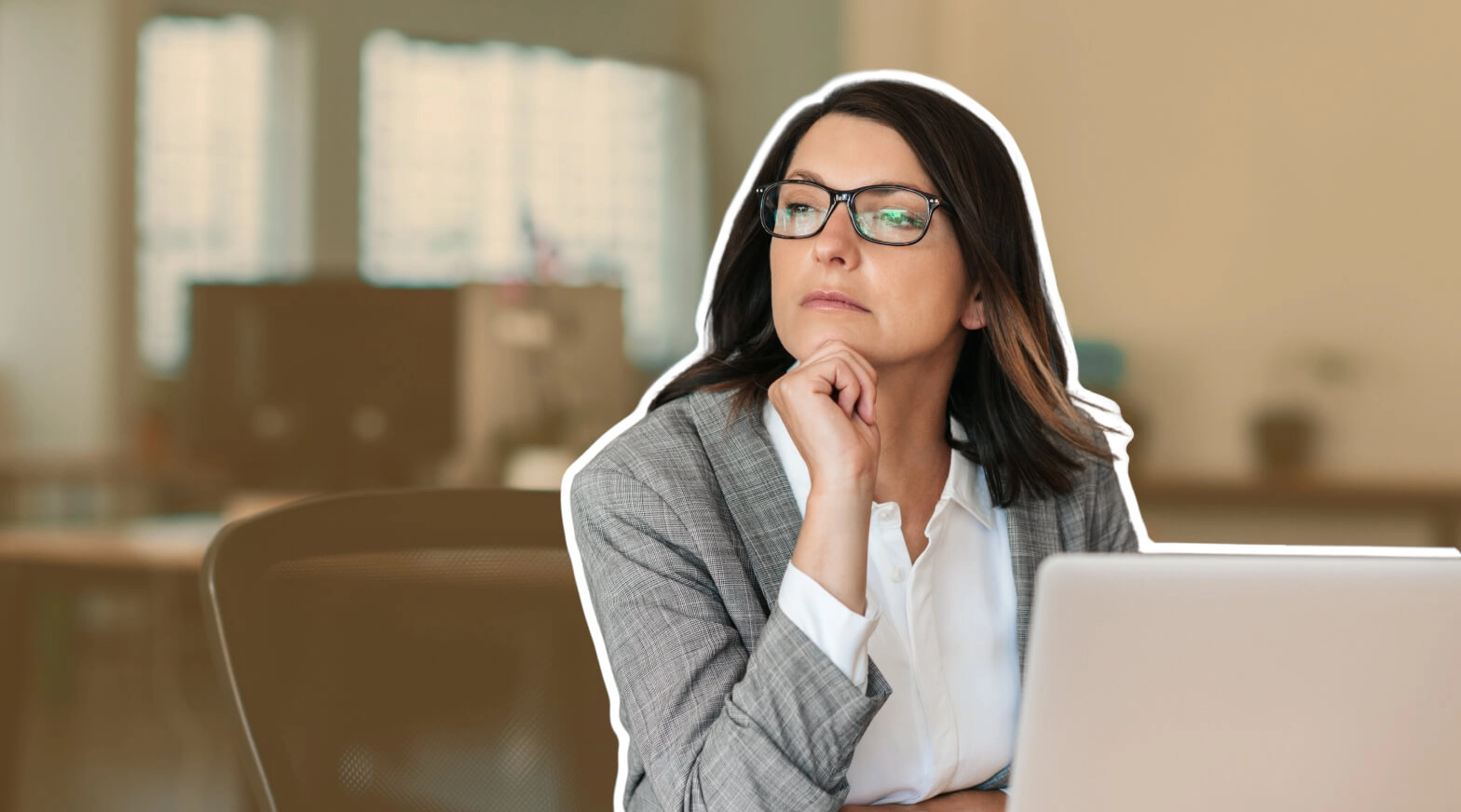 a woman in glasses sitting at her desk with a laptop