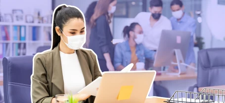 a woman wearing a mask while working at a laptop in an office setting