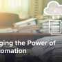 A desk with multiple stacks of paperwork sitting on it, with an icon floating above the desk showing papers pointing to a cloud.