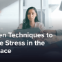 Worried businesswoman in a busy office with many people handing around paperwork.