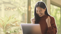 a woman is smiling while looking at her laptop